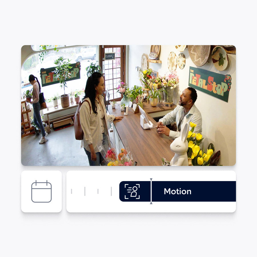 A person is greeted by a business owner behind a counter. The Ring app interface below shows this event on a timeline